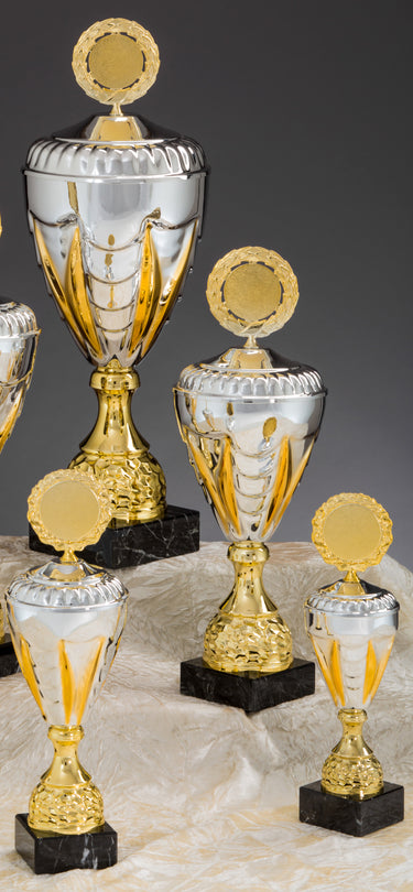 Fünf silberne und goldene Pokale Germering-Trophäen in verschiedenen Größen (275 mm bis 405 mm) mit runden Schildern auf schwarzen Marmorsockeln werden auf einem hellbraunen Stoff präsentiert.
